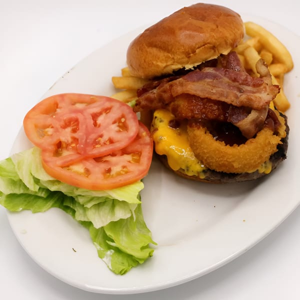 Montclair House Grill's bacon cheeseburger with onion rings, fries, lettuce, and tomato on a white plate.